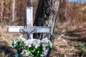 burial place with a cross and white flowers by the tree