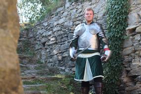 Knight in armor, near the beautiful, old stairs with green plants