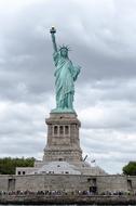 crowd of people beneath statue of liberty at cloudy day, usa, new york city