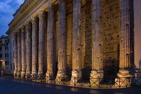 Beautiful, antique Temple of Hadrian with the columns and lights, in the evening, under the blue sky with clouds