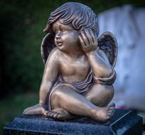 bronze sculpture of an angel in a cemetery on a blurred background