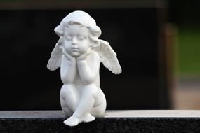 statue of a little white angel on a tombstone