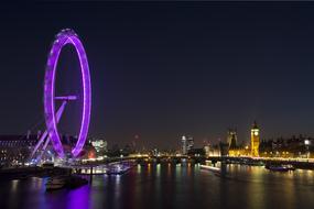 Beautiful landscape with the violet London Eye, among the beautiful London with colorful lights in England, UK, at night