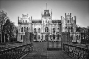 Black and white photo of the beautiful Evenburg palace, among the trees, with the bridge in Germany