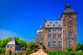 Beautiful landscape of the brick castle, among the green plants, at beautiful blue sky on background