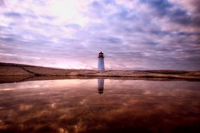 Lighthouse on coastline at scenic evening sky