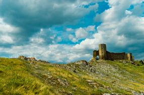 castle on top of a hill with white clouds in the background