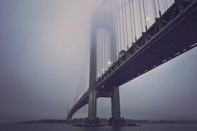 low angle view of Suspension Bridge in mist at dusk