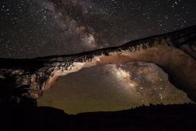 scenic low angle view of Owachomo Bridge rock formation at starry sky, usa, utah