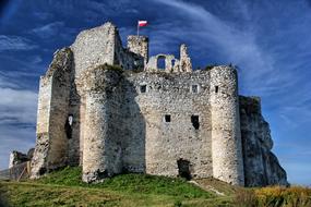 Beautiful, old castle, on the colorful hill in Mirow, Poland, under the blue sky with white clouds