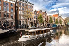 white tourist boat on channel in old city, netherlands, amsterdam