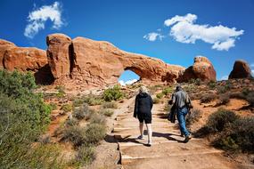 woman and man walking on path to scenic Red Rocks, usa, Utah, Moab