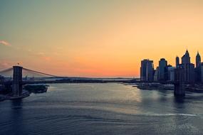 Beautiful Brooklyn Bridge and buildings with the sunset on background