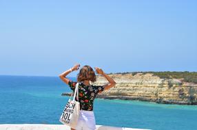 Back view of the girl with the bag, on the beautiful and colorful shore of Algarve, Portugal