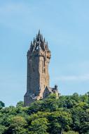 tower of William Wallace Monument on forested hill at sky, uk, scotland, stirling