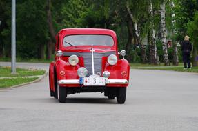 red historic car on the road