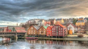 colorful buildings on shoreline beneath grey clouds, Norway, Trondheim