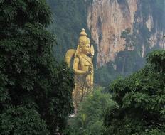 large gold Buddha statue among the trees in Malaysia