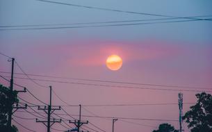 setting sun in pink sky above power lines