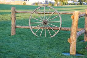 antique wheel stands at a wooden fence