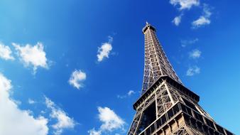 Beautiful Eiffel Tower in light at blue sky background with white clouds