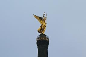 Shiny gold angel figure at blue sky background in Berlin, Germany