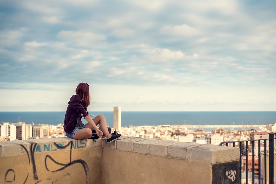 Girl, sitting on the building, on the beautiful panorama with the sea, in Alicante, Spain