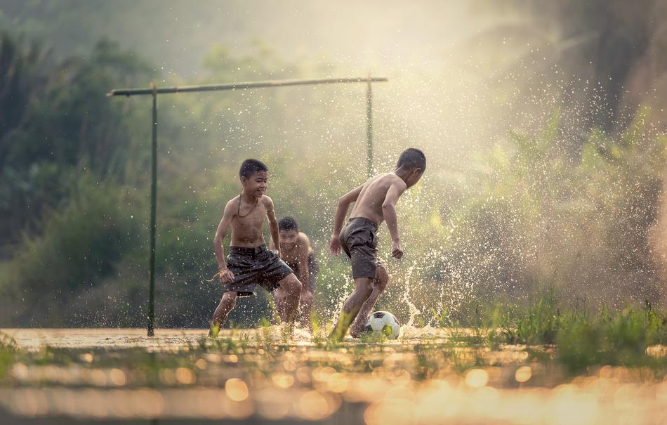 Children are playing football at rainy day