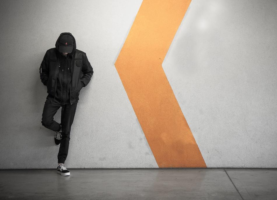 Person leaning on the white and orange wall in the subway