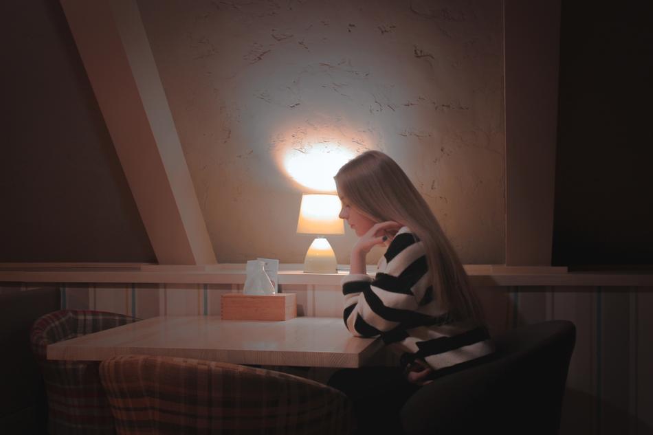 Girl, sitting at the table in the café with beautiful interior with light