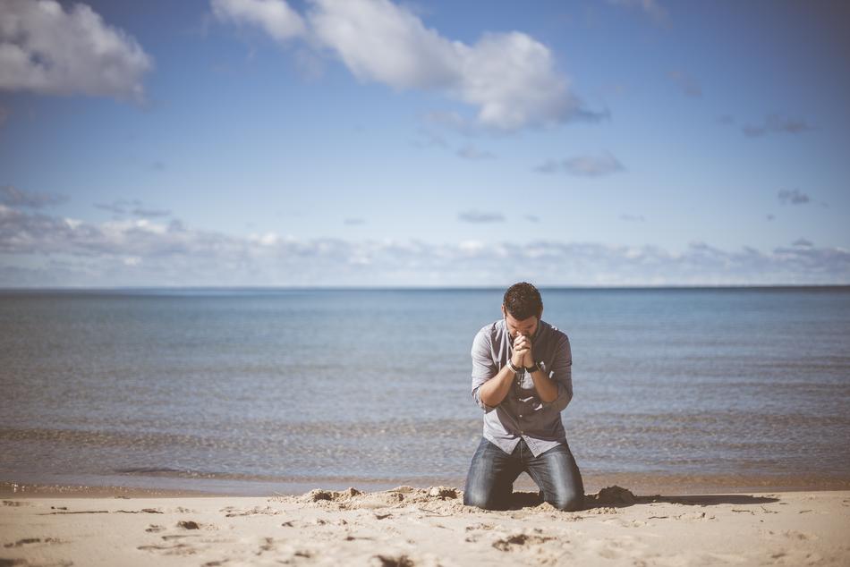 man in prayer on the beach