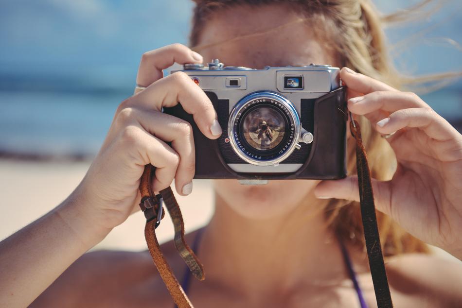 blonde with a camera on the beach on a blurred background