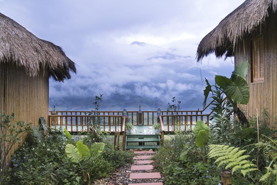huts in tropical garden in front of scenic misty mountains, vietnam
