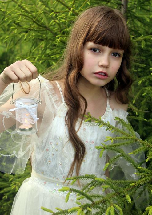pretty child girl with Candle near Spruce