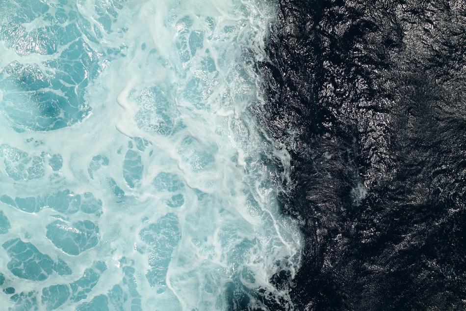 Beautiful, turquoise and white wave on the shore with rocks