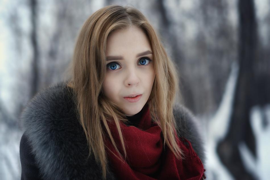 blonde in a coat with fur on a background of snowy trees