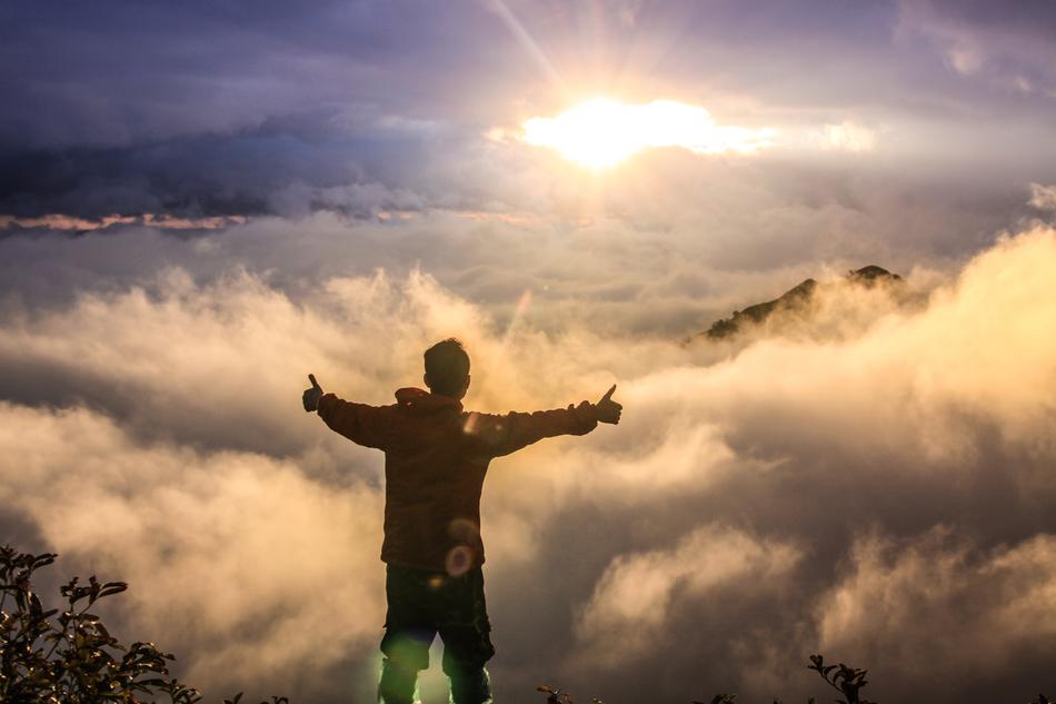 free man on top of the mountain in the clouds at the sunlight