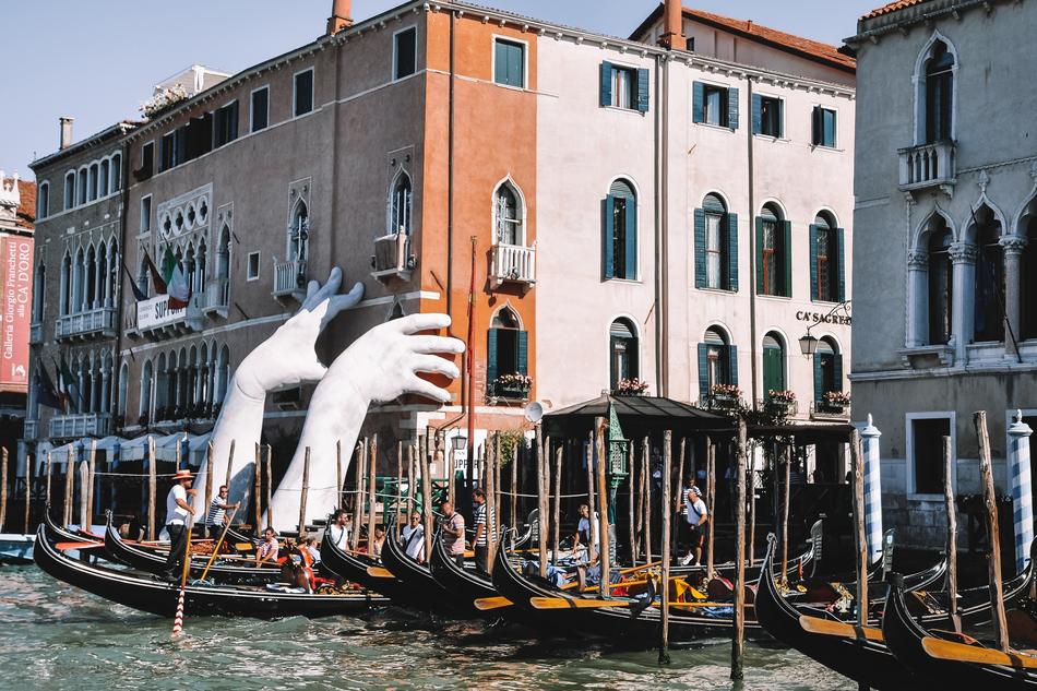 sculpture of white hands on a canal in Venice