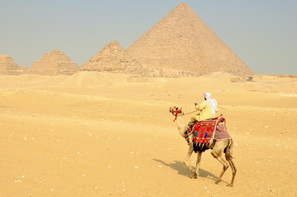 man on a camel near the pyramids on a sunny day