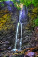 Beautiful waterfall on the colorful rocks with plants