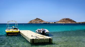 motor boats are moored at a floating pier off the coast of the island of Mykonos, Greece