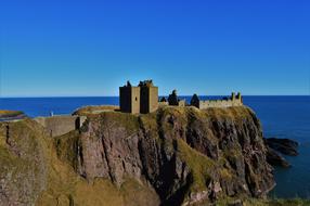 Beautiful Dunnottar castle on the cliff above the water at blue sky background in Scotland, UK