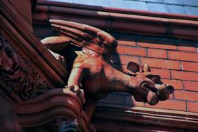 statue of a gargoyle on the roof of a brick building