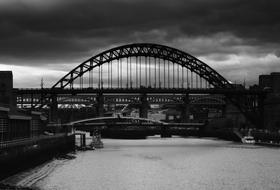 Black and white photo of the bridge, above the water in Newcastle, Northumberland, England, UK