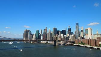 Beautiful landscape with the colorful shore of New York with the Brooklyn Bridge, at blue sky with white clouds on background, in America