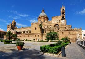 Beautiful, old monument in Palermo, Sicily, Italy, among the plants, at blue sky with white clouds on background