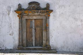 Old, decorated door in the white wall of the building