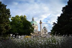 Beautiful, historical monument near the green trees and white flowers in Vienna, Austria