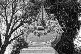 Black and white photo of the beautiful, patterned Angel sculpture, near the trees