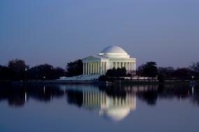 Beautiful Jefferson Memorial with columns, on the shore with trees, with the reflection in the water in Washington, USA